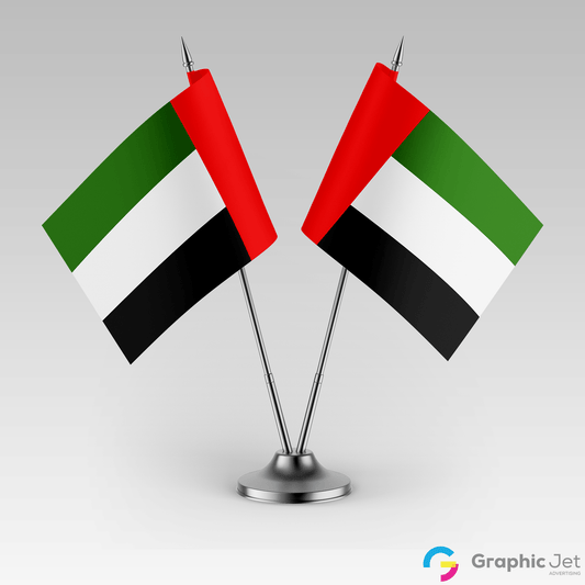 Two United Arab Emirates flags on a stand against a gray background