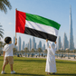 Two children holding a United Arab Emirates flag with a city skyline in the background